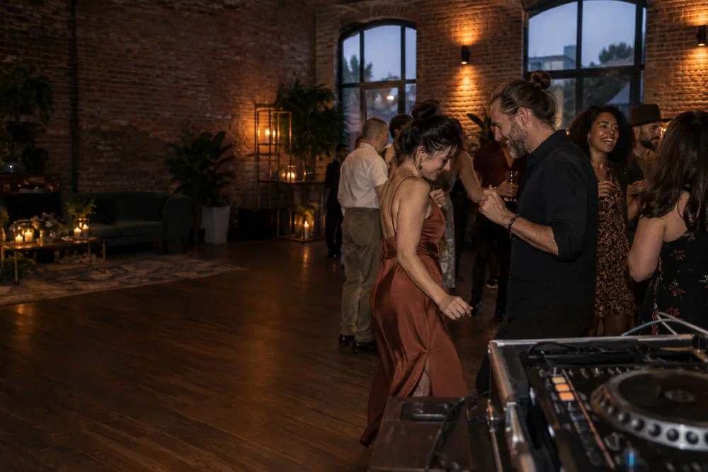 Illustrative scene of friends dancing beside a DJ booth in a brick event room